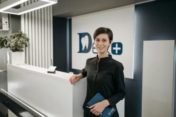 Smiling receptionist in a modern dental clinic lobby.