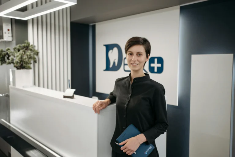 Smiling receptionist in a modern dental clinic lobby.